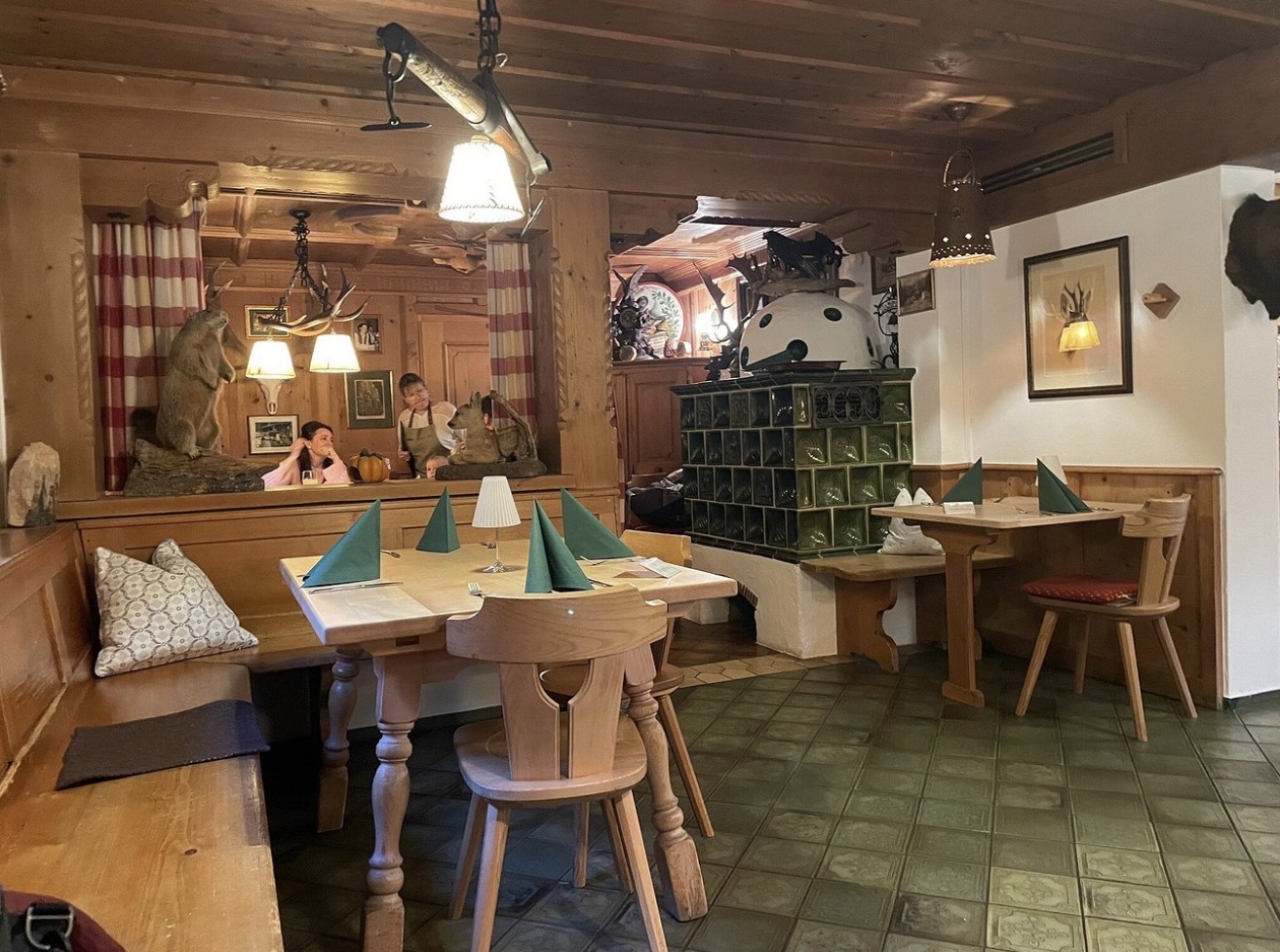 Gemütliche Stube mit Kachelofen, grünen Servietten und Murmeltier-Präparat
