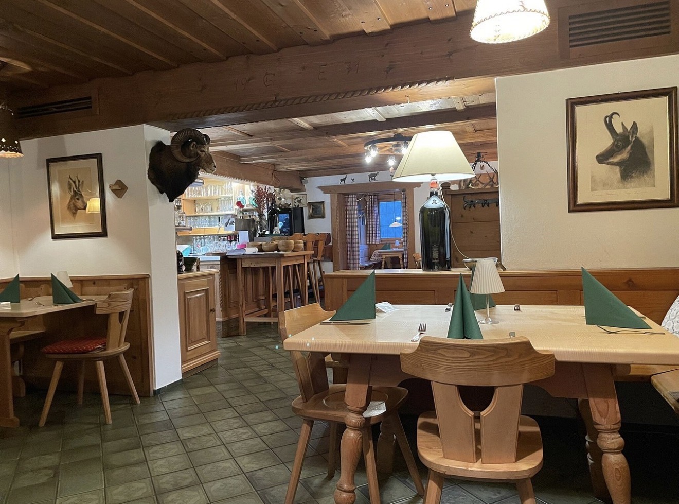 Eingedeckte Tische im Gastraum mit Theke und Jagdtrophäen