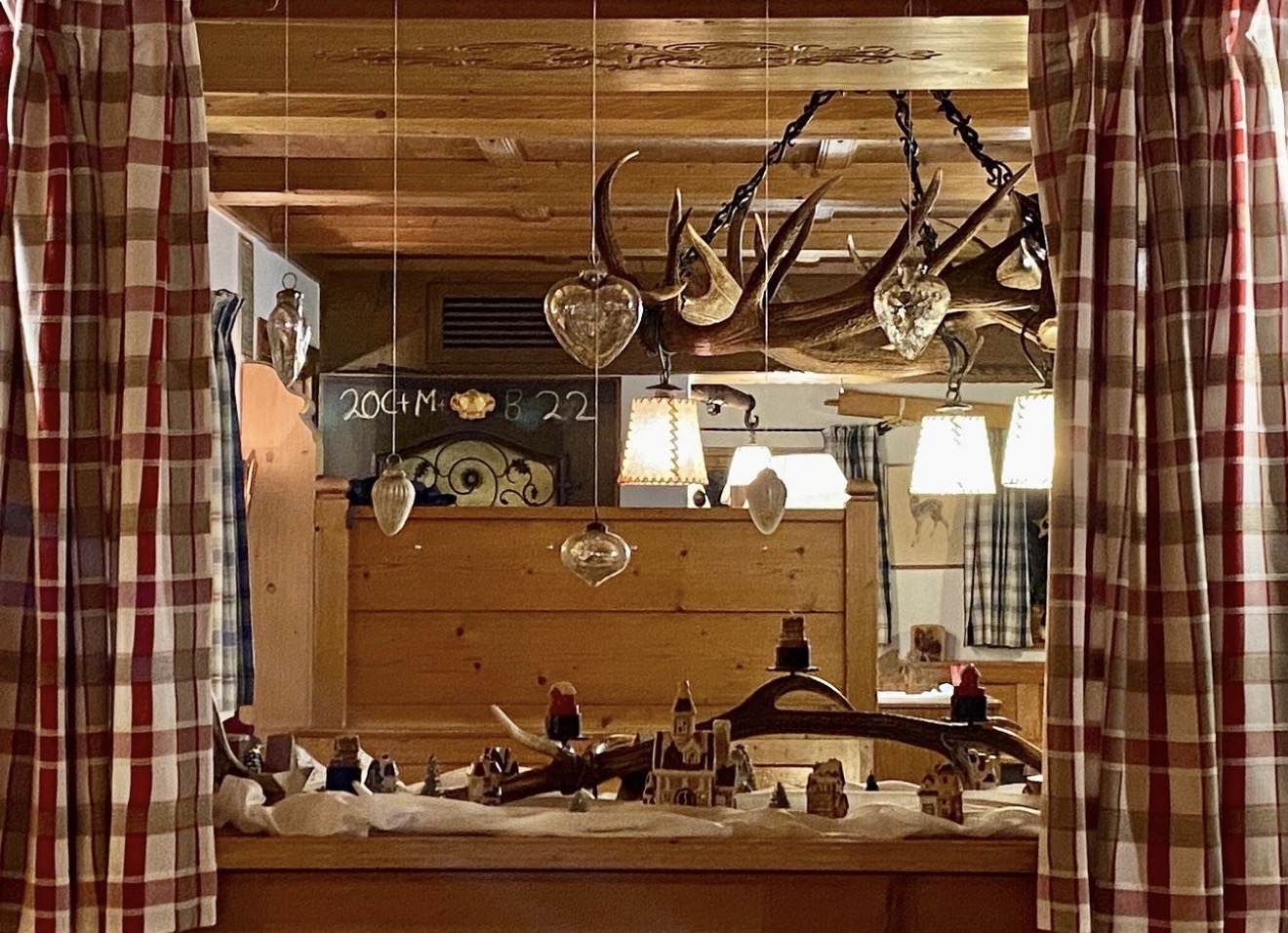 Geweih-Leuchter mit Christbaumkugeln und Krippenlandschaft in der Stube