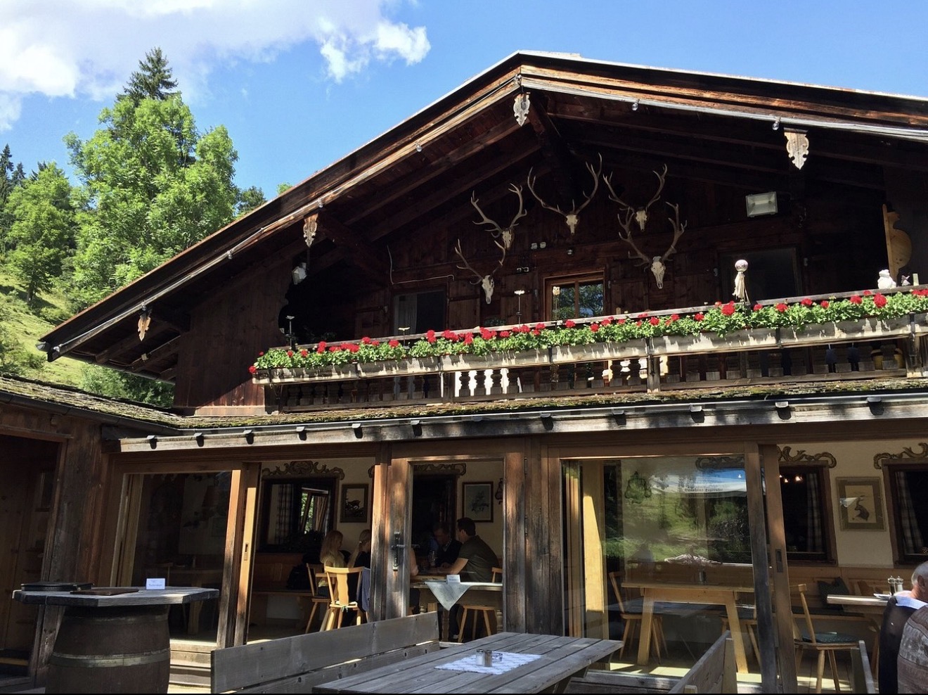 Almgasthaus Café Aibl – Holzfassade mit Geweihen und Biergarten